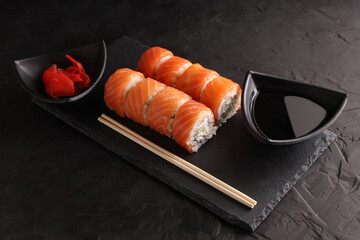Sushi and rolls set on a black plate and black background