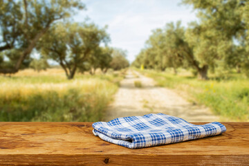 Empty wooden table with tablecloth near olives tree field