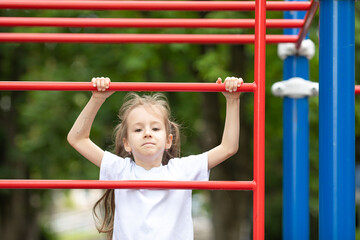 A cute little girl is engaged in sports simulators at the sport ground outdoors. Healthy lifestyle