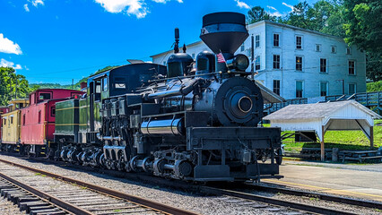 Fototapeta na wymiar View of a Shay Steam Locomotive Warming Up to Pull a Group of Cabooses on a Sunny Summer Day