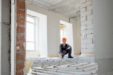 Worker is installing underfloor heating system. Warm floor heating system