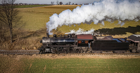 Aerial Parallel View of a Restored Antique Steam Passenger Train Traveling Thru The Countryside on a Sunny Autumn Day