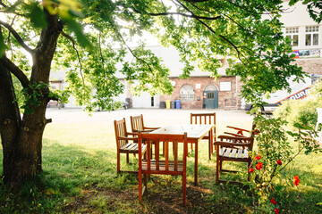 Sitzecke mit Tisch und Stühlen draußen im Garten unter einem Baum. Schutz vor Sonne