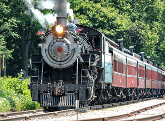 Fototapeta premium A View of A Restored Steam Passenger Train Approaching Traveling Thru Rural America on a Sunny Day
