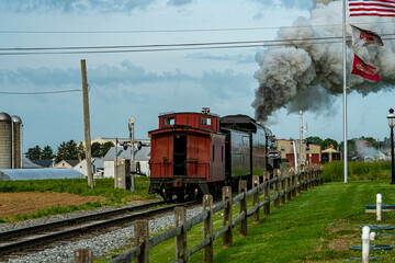 A View From the Rear of a Modern Steam Locomotive and Caboose Blowing Smoke on a Spring Day