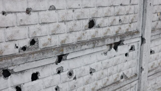 Bullet riddled, after shelling, pierced wall. Ukrainian war has destroyed concrete fences with bullet holes or shelling that were destroyed during the war