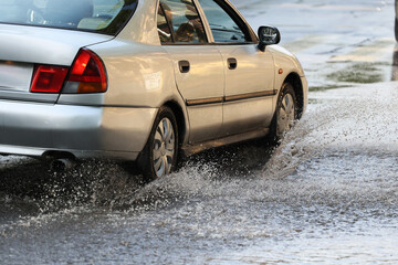 Ulewa w mieście - Samochód wpada w kałużę wody na jezdni powodując rozbryzg.