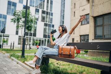  Japanese woman singing while listening music with headphones and mobile phone outside on the street