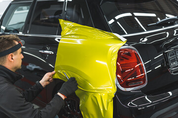 Back and truck of a car during car wrapping process at detailing station. Professional car detailer...
