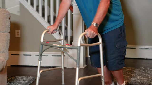 A man uses a walker in his home.  	