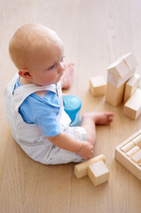 Little baby boy, toys and wooden blocks on floor for playtime, learning or childhood development at home. Cute, adorable or growing infant of newborn, child or toddler playing on the ground in house