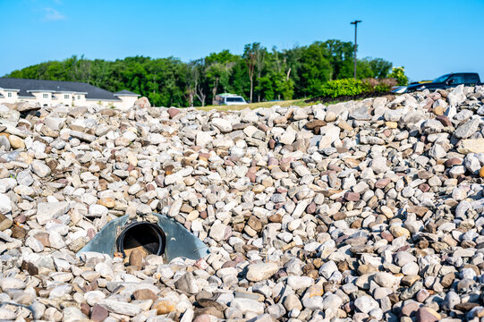 underground drainage storm drain with winged walls surrounded by rock for erosion control 