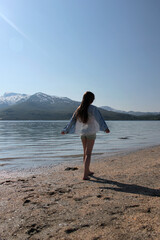 Girl in a denim shirt on the seashore, fjord, sunny day on the beach