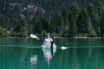 Woman kayaking paddling on picturesque lake with green water. Green lake. Whistler. British Columbia. Canada