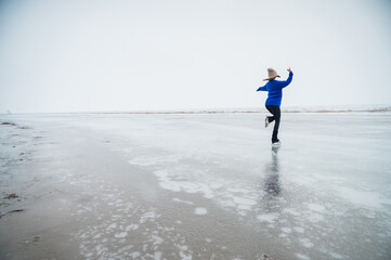Caucasian woman in a blue sweater skating on a frozen lake. 