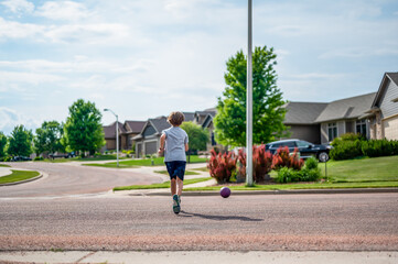 Chasing a ball that has crossed the street by rolling into a road.