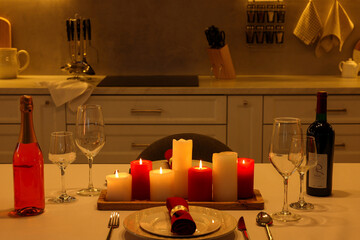 Romantic atmosphere. Beautiful table with candles, bottles and tableware served for Valentine day