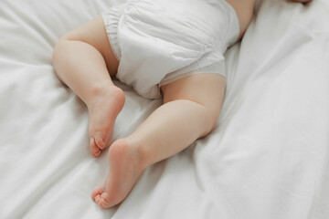 Fototapeta na wymiar Little baby in diaper on white bed, closeup