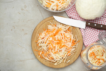 Cooking delicious sauerkraut soup. Fresh chopped carrot and cabbage on light grey table, flat lay