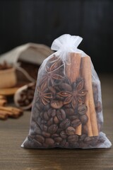 Scented sachet with coffee beans, anise and cinnamon on wooden table, closeup