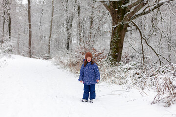 Adorable little girl having fun in beautiful winter park. Cute child playing outdoors. Winter activities for kids.