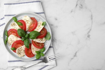 Caprese salad with tomatoes, mozzarella, basil and spices served on white marble table, top view....
