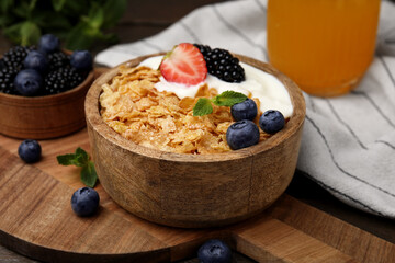 Delicious crispy cornflakes, yogurt and fresh berries in bowl on table, closeup. Healthy breakfast