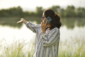 mother talking by phone, drinking coffee and playing with her child by the river