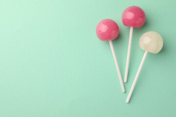 Tasty lollipops on turquoise background, flat lay. Space for text