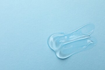 Swatches of cosmetic gel on light blue background, top view. Space for text