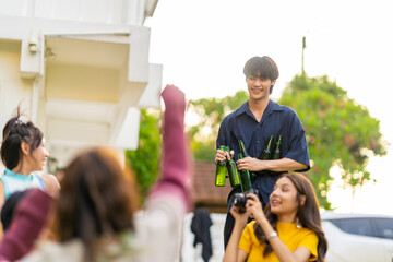Obraz premium Group of Happy young Asian man and woman friends enjoy and fun reunion meeting party at home backyard with playing guitar, singing, eating food and drinking beer together on summer holiday vacation.