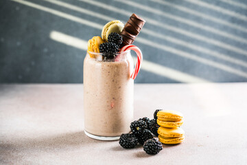 Chocolate indulgent extreme milkshake with macaroons, berry  and sweets. Crazy freakshake food trend. Copy space