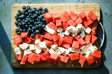 Patriotic salad idea with blueberries, feta and watermelon in the shape of American flag on gray...