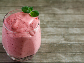 Healthy Strawberry or Raspberry Cream mousse in glass on a wooden table with mint leaves. Delisious summer dessert. Top view, copy space