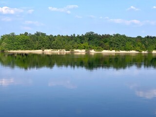 River calm blue water and forest in the shore at summer.