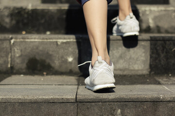 Fototapeta na wymiar Feet of a girl in white shoes walking up the stairs