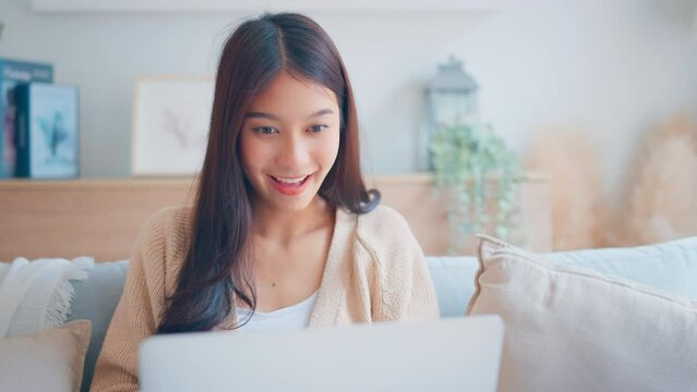 Excited young asian woman winner looks at laptop celebrates online work at home on desk with successful. feeling surprised, Reads good news in email, Achieve target project.