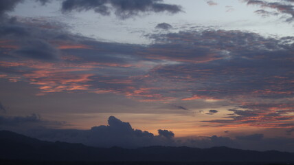 Digital composite of Sunset sky with clouds and mountains in orange and blue