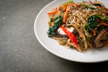 japchae or stir-fried Korean vermicelli noodles with vegetables and pork topped with white sesame