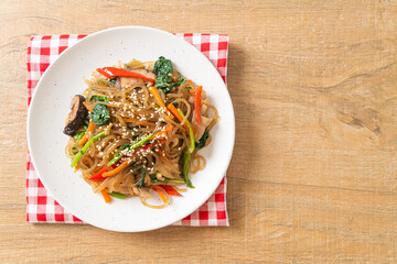 japchae or stir-fried Korean vermicelli noodles with vegetables and pork topped with white sesame