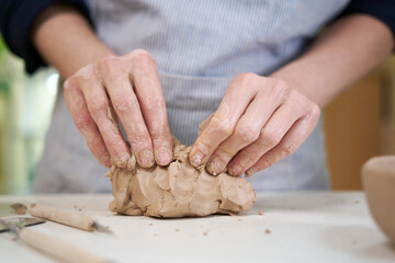 Closeup hands of ceramic artist wedging clay in art studio