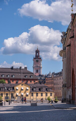 Obraz premium Old houses and the tower of the church Storkyrkan, a square at the island Riddarholmen, a sunny summer day in Stockholm