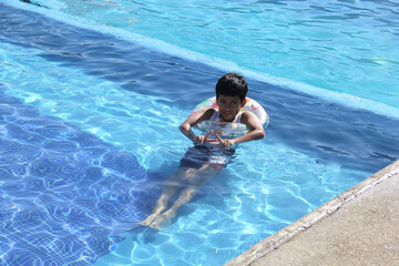 9-year-old brown-haired Latino boy swims in the pool, plays and enjoys his vacation under the sun with sunscreen