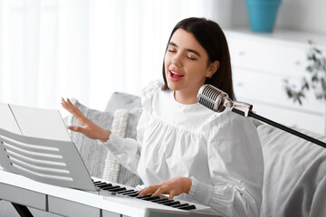 Young female musician playing synthesizer and singing at home