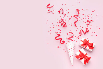 Party cone with serpentine, confetti and gifts on pink background