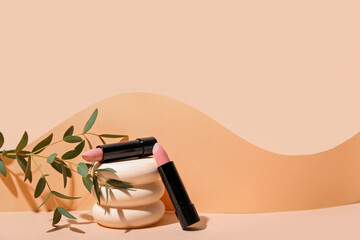 Decorative plaster podiums, lipsticks and eucalyptus branch on beige background