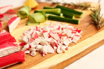 Wooden board with tasty chopped crab sticks on table, closeup © Pixel-Shot