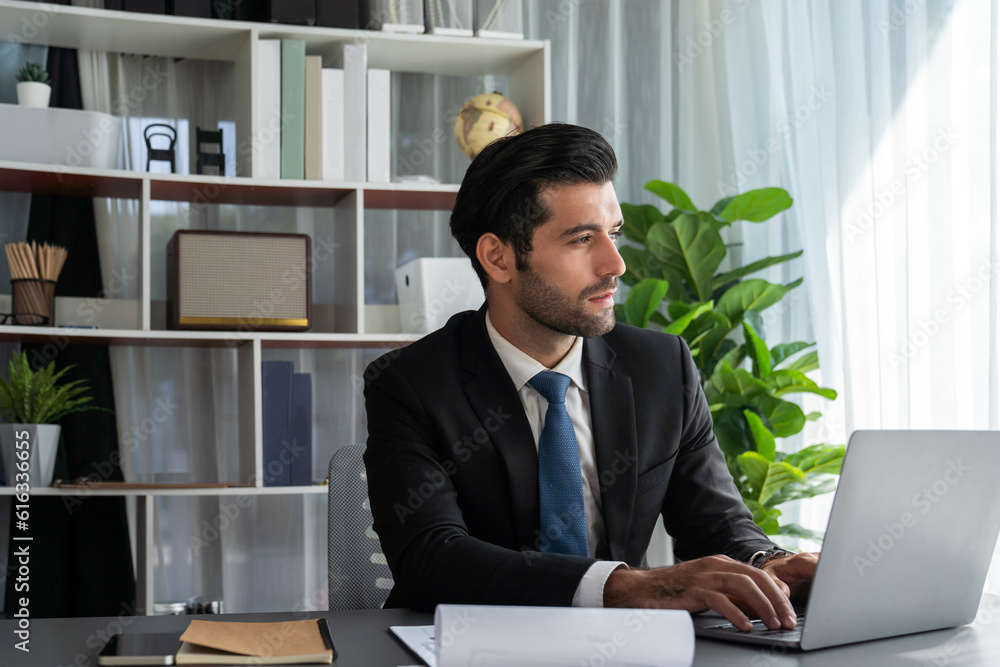 Poster modern professional businessman at modern office desk using laptop to work and write notes. diligent