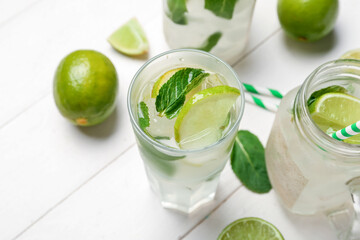 Mason jar and glass of tasty mojito on light wooden background