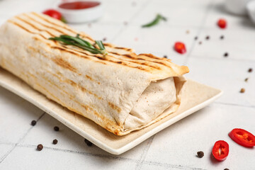 Plate of tasty shawarma with rosemary and chilli on white tile table